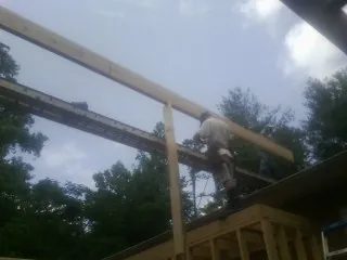 Carpenter setting a ridge beam over a new addition frame — Ice Dam Removal by Roofing Brothers in Ozark
