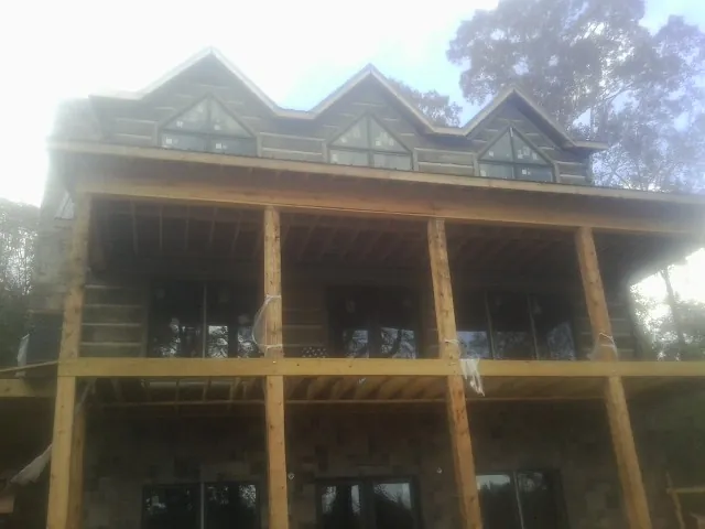 Dormers and porch framing on a large log home under construction — Roof Coating work by our crew in Ozark