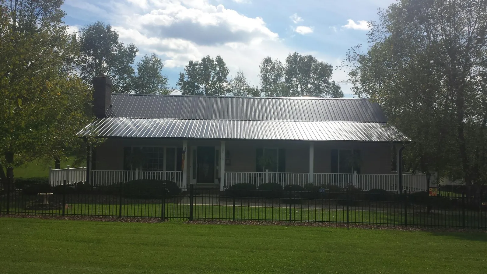 Gray metal roof on a brick ranch with a full width front porch — Gutter Guard Installation work by our crew in Ozark